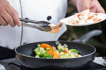 Chef putting shrimp to pan