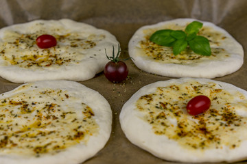 Four little baked white bread patties with olive oil, herbs, basil and tomatoes for quick snack