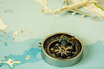 selective focus of miniature tourist on compass over map with plastic toy airplane,abstract background to travel concept
