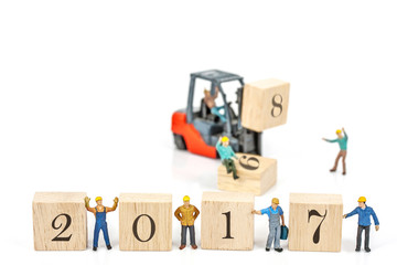miniature worker team building standing front of forklift machine with 2017 number on wooden block on white background, decoration to Happy new year 2017 concept.
