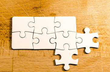 New opportunities and open mind, white jigsaw/puzzle whit new branches over a wooden table...