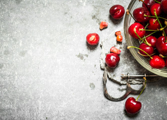 Naklejka na ściany i meble Red cherry in the Cup and metal tool for cherries.