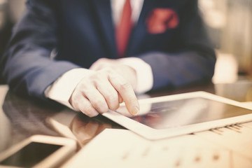 Close-up of modern businessman using tablet computer at office table