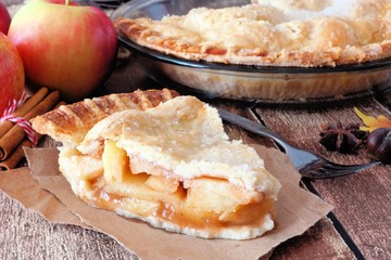 Slice of sweet apple pie on paper, still life with an old wood background