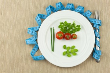 Strict diet against obesity. Dietary vegetable diet. Tomatoes on a plate. Raw vegetables on a white plate and a measuring tape.
