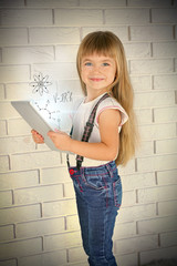 Little girl with tablet on brick wall background. Study and technology concept.