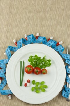 Strict diet against obesity. Dietary vegetable diet. Tomatoes on a plate. Raw vegetables on a white plate and a measuring tape.
