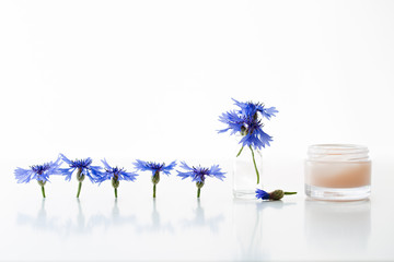 Glass jar of beauty cream and cornflowers