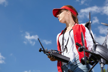 A woman is standing and holding drone over sky