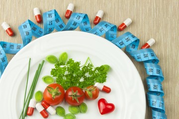 Strict diet against obesity. Dietary vegetable diet. Tomatoes on a plate. Raw vegetables on a white plate and a measuring tape.
