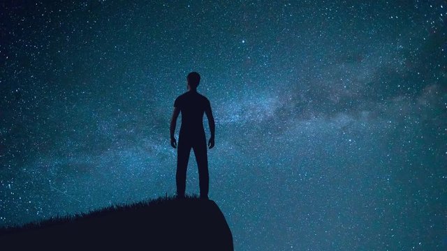 The man stand on the mountain on the background of meteor shower. Time lapse