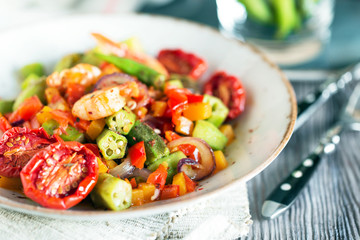 Vegetable stew with okra and shrimps in rustic composition – close up view