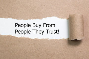 Motivational quote People Buy From People They Trust, appearing behind torn paper. 