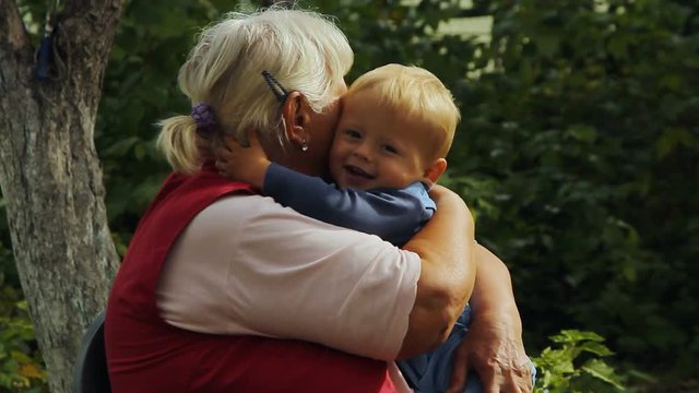 Grandma happily hugging little grandson in the garden