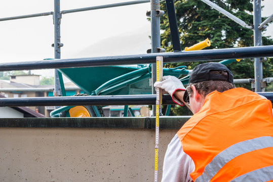 Bricklayer With A Folding Meter And High Visibility Reflective Jacket