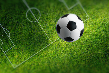 Small soccer ball on green stadium with white layout. Collage made like photo taken with shallow depth of field.