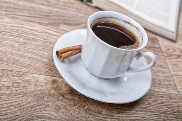 A cup of coffee and cinnamon with a book