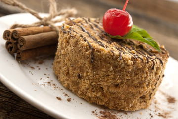 Layered cake with nut and cinnamon on plate, on wooden table, da