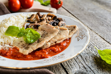 Fried pork cutlets with rice, tomato and mushrooms