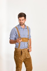 Junger Mann in Lederhose bedient sein Handy