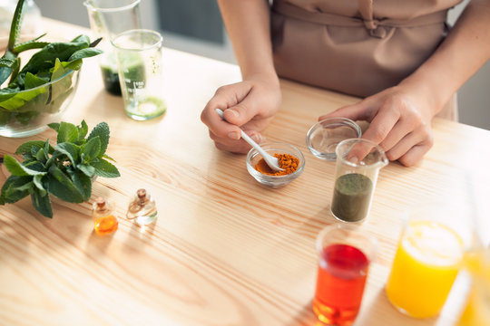 woman makes handmade cosmetics on wooden table;