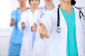 Group of doctors offering helping hand in hospital closeup. Friendly and cheerful gesture. Medical cure and tests advertisement concept. Physicians ready to examine and save patient