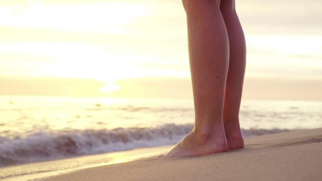 Legs in sea sand at sunset 
