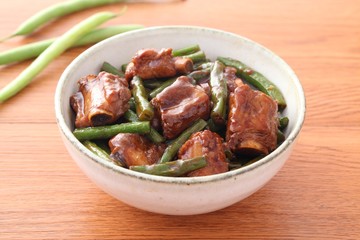 Bowl of fried pork ribs with green bean on wooden table