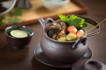 Black pot of shrimp and mushroom and herbs on the table