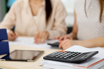 Two female accountants counting on calculator income for tax form completion hands closeup. Internal Revenue Service inspector checking financial document. Planning budget, audit  concept