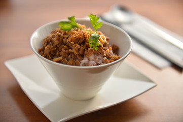 Minced beef with fried rice on white bowl in restaurant