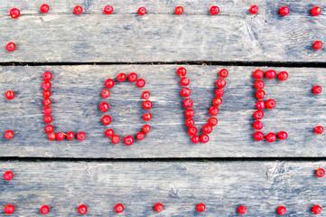 Rowan berries on vintage wooden background. The word "love" is made up of rowan berries