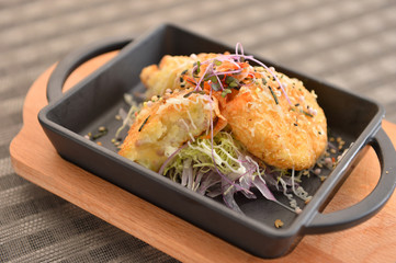Rice cake with salad on black stew on cutting board