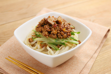 Udon noodle with minced beef and vegetables in white bowl on tab