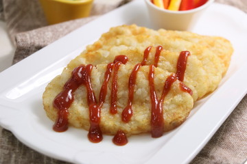 Crispy potato cake with chili sauce on white plate