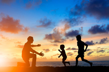 Silhouette family mother, father and young son holding hands, ta