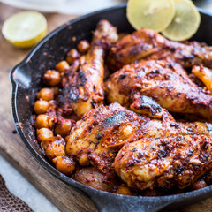 Harissa roasted chicken in black pan with lemon and corn
