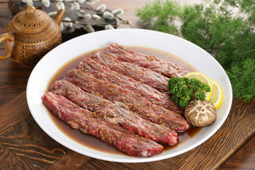 Seasoned sliced beef on white plate with lemon, mushroom and her