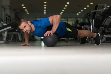 Fototapeta na wymiar Personal Trainer Doing Push-ups On Floor In Gym