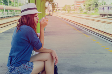 Beautiful girl drinking coffee on the railway station,beautiful woman waiting for train travel