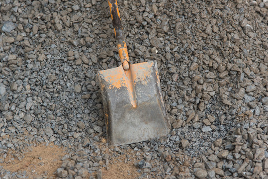 Shovel stuck in a pile of dirt,Construction worker is trying to move a kurb