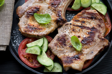 Closeup of barbecued pork meat steaks on bone with vegetables