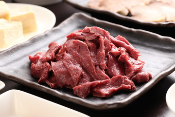 Silced beef heart with tofu on black plate in a hot pot meal
