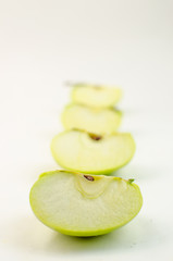 Green apple cut into slices, on a white background.
