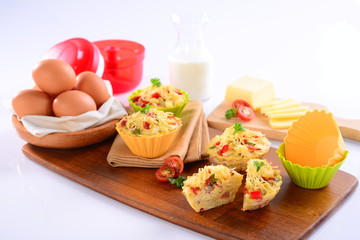 Macaroni dish muffin with egg and sliced tomato on wooden tray