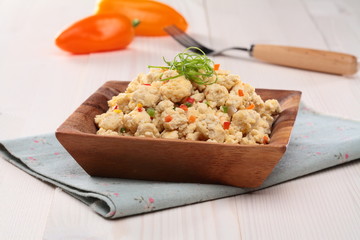 Tofu stir soboro on wooden bowl with tomato and onion on tablecl