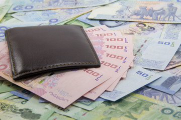 100 banknotes in brown leather wallet with 50 and 20 banknotes on the ground, Thai money, selective focus