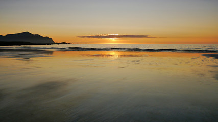 Sunset over the beach, light reflection in wet sand. Lofoten, Norway