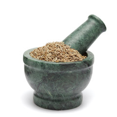 Organic Cumin seed (Cuminum cyminum) on marble pestle. Isolated on white background.