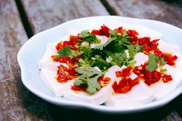 Fresh white tofu with minced chili and herbs on white plate